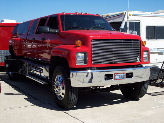 Red extended cab truck with a camper shell and chrome bumper. License plate reads BIGGRED