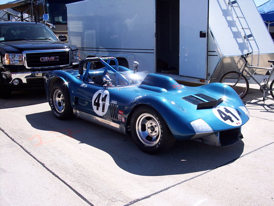 Blue race car with number 41 on side and front, parked next to a GMC truck and trailer