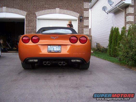 Orange convertible sports car parked in driveway, rear view. License plate ADTA-773