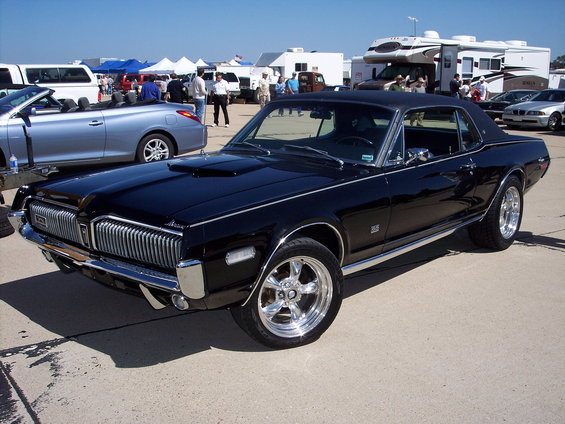 Black 1969 Mercury Cougar XR7 with chrome wheels and a black vinyl top parked outside