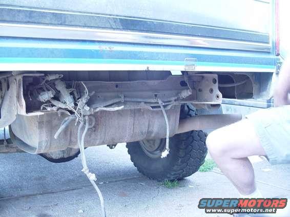 Rear bumper area of a blue and green vehicle showing exposed fuel lines and a tire