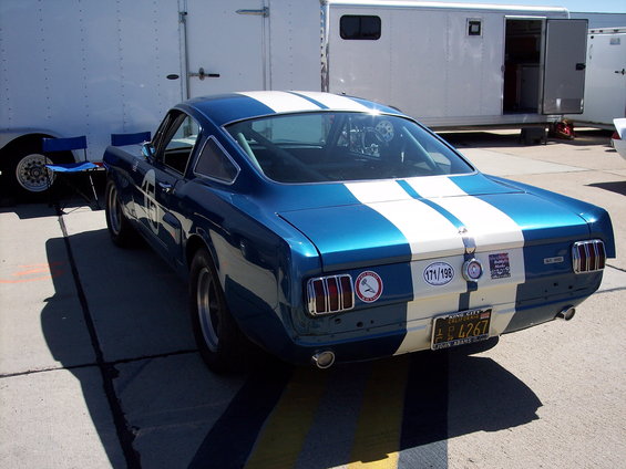 Blue and white striped coupe with racing decals, viewed from the rear