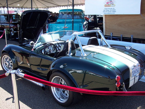 Dark green convertible with white racing stripes and chrome roll bar, hood open