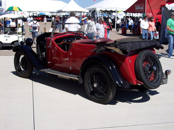 Red convertible with black fenders and a rear-mounted spare tire