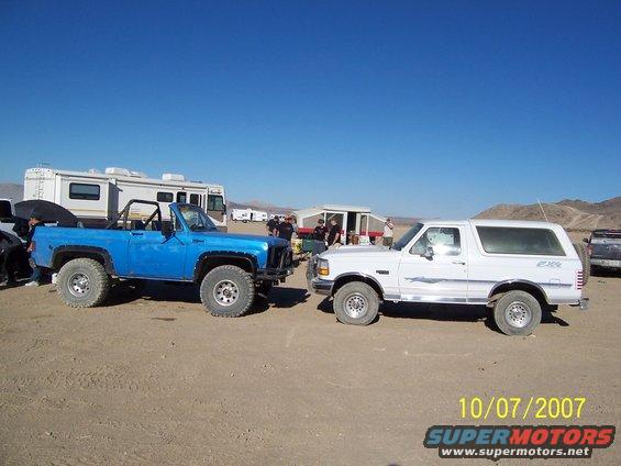 White 1996 Ford Bronco parked next to a blue Chevrolet K5 Blazer in a desert landscape