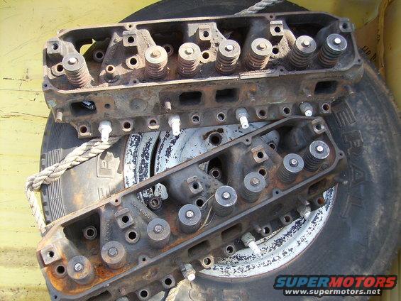 Two rusty engine cylinder heads resting on a tire