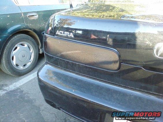 Rear view of a black Acura sedan parked next to a dark green sedan. The Acura has 'ACURA' badging visible