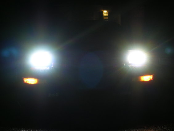 Car headlights and amber turn signals illuminated at night