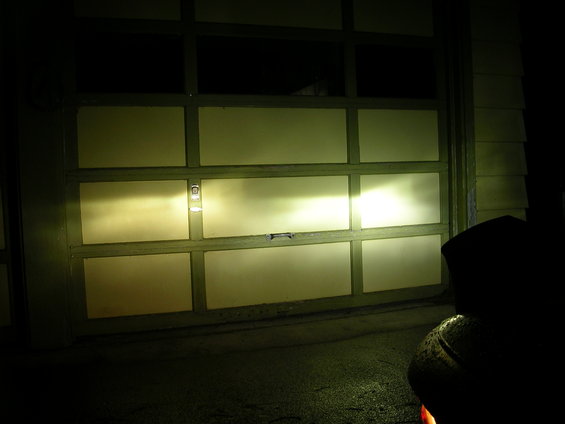 car headlights shining on a garage door at night