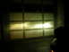 2007 Mazda 3 - Headlights illuminate a garage door, casting bright beams across its panels.