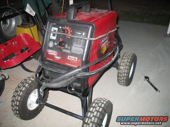 Red Lincoln Electric Weld Pak 3200 welding machine on a cart with four wheels