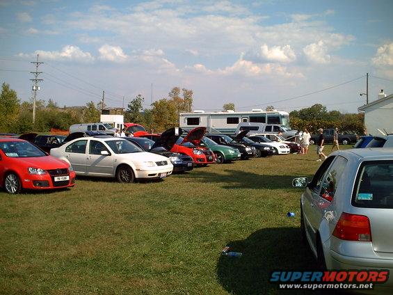 Cars parked on grass with RV in background