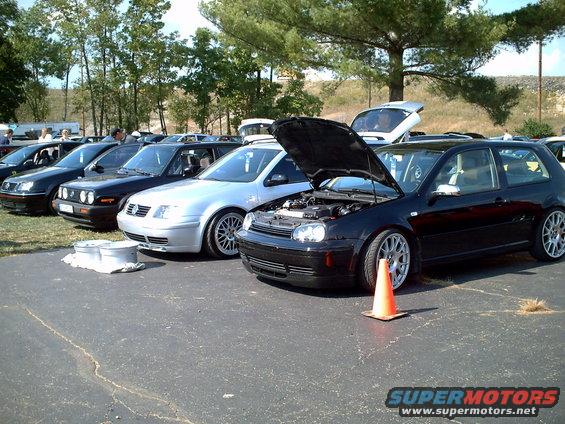 Black Volkswagen Golf GTI, hood open, parked in a line of cars