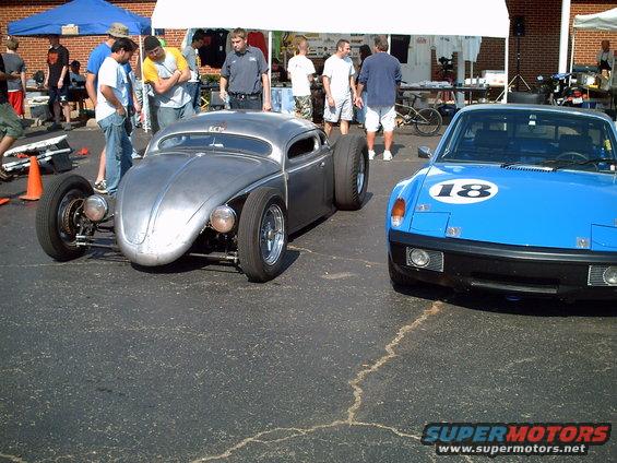 Silver VW Beetle hot rod with wide rear tires next to a blue Porsche 914 with a number 18 decal