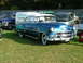 1988 Ford Sport - A vintage blue sedan is parked on a grassy field next to other vehicles and a white van.