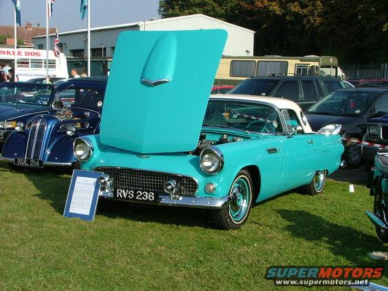 Turquoise and white convertible with hood open, parked on grass. License plate RVS 236