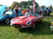 1988 Ford Sport - A red convertible is displayed at an outdoor car show with other vehicles and people around.