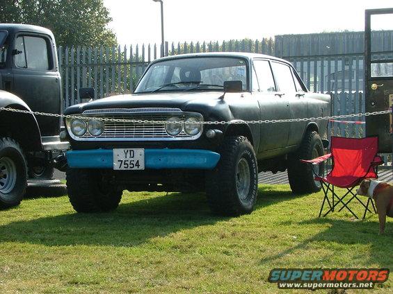 Black sedan with off-road tires and blue bumper, front view