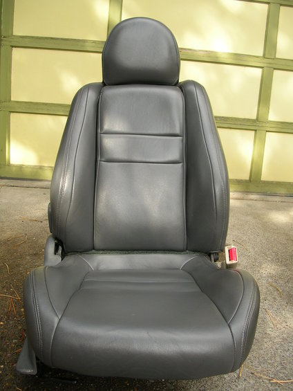 Black leather car seat with headrest and red seatbelt buckle