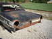 1963 Ford Galaxie - Rear view of a rusty 1963 Ford Galaxie, missing its taillights and bumper, with a white grille visible.