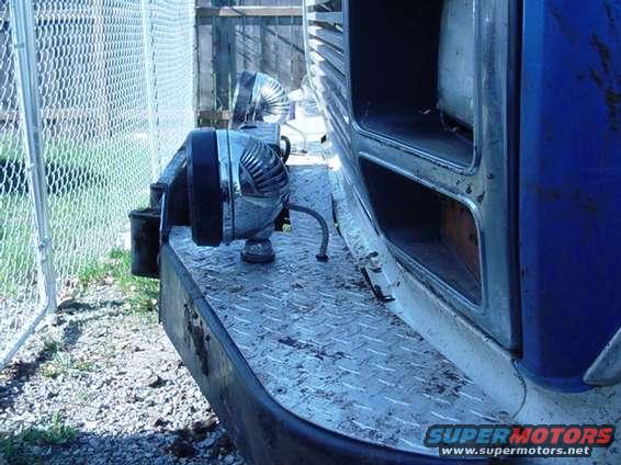 Chrome auxiliary lights and siren mounted on diamond-plate truck bumper