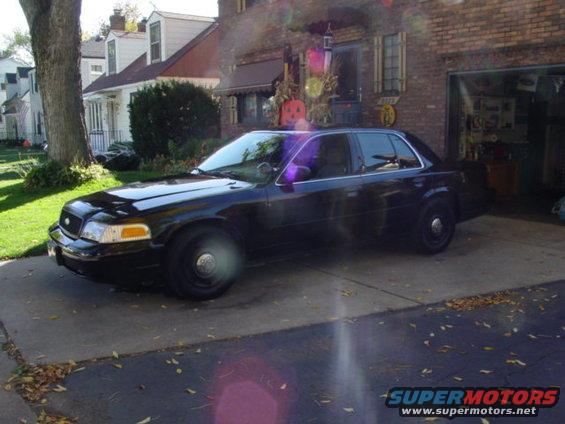 Black sedan parked in driveway, house and garage in background