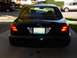 2003 Ford Crown Victoria - Rear view of a black 2003 Ford Crown Victoria, showing its distinctive taillights and license plate.