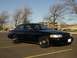 2003 Ford Crown Victoria - A black 2003 Ford Crown Victoria is parked in an empty lot under a clear sky.