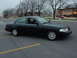 2003 Ford Crown Victoria - A black 2003 Ford Crown Victoria sedan is parked in a lot, showing its 3/4 front profile.