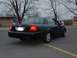 2003 Ford Crown Victoria - Rear view of a black 2003 Ford Crown Victoria sedan with full wheel covers parked on asphalt.