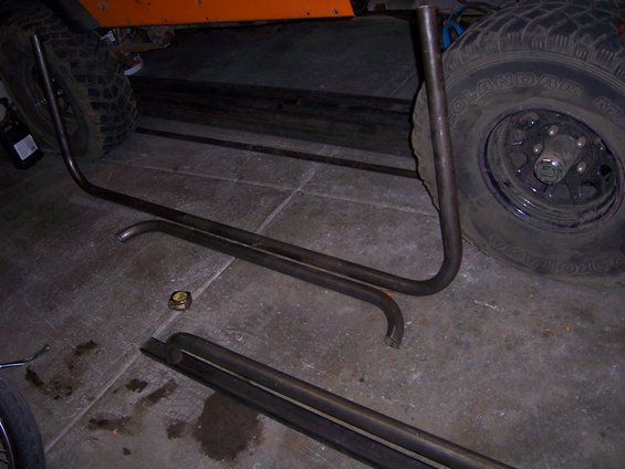 Orange vehicle body and tire with metal tubing on concrete floor
