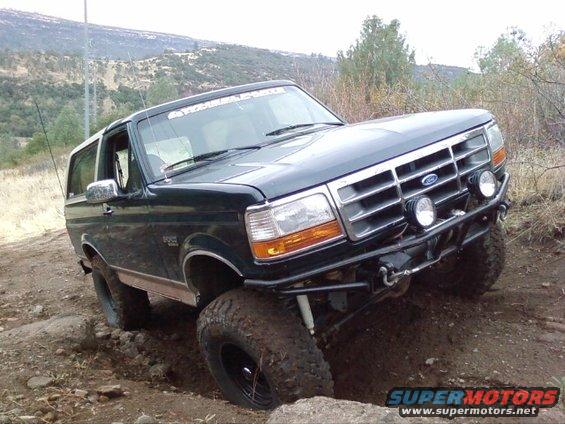 1995 Ford Bronco with aftermarket bumper and lights on a dirt trail