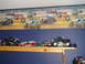 1979 Ford Bronco - A collection of monster truck toys displayed on a shelf, with a mural of monster trucks in action on the wall.
