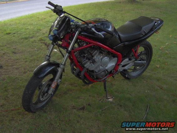 Motorcycle with red frame and black bodywork parked on grass