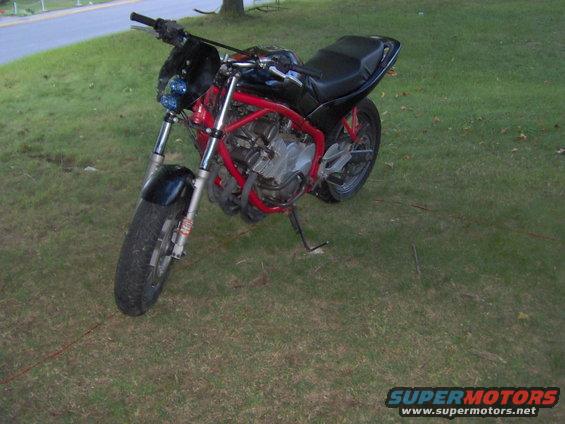 Red framed motorcycle with black seat and fairing, parked on grass