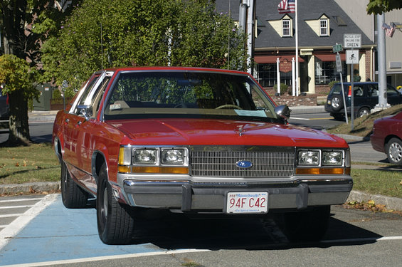 Red Ford Crown Victoria parked in a handicapped spot, front view. License plate 94F C42