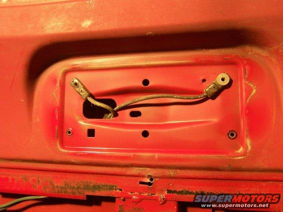 Close-up of red vehicle panel with wiring connectors and a wire running between them. Text on bottom right reads SUPERMOTORS
