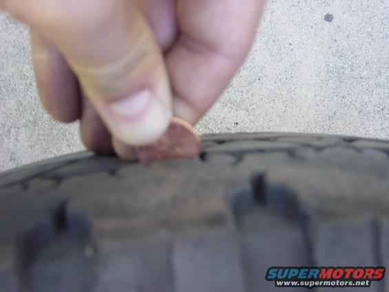Close-up of tire tread with a penny inserted