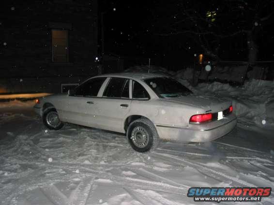 White sedan parked in snow, 3/4 front view. Visible taillight and side profile