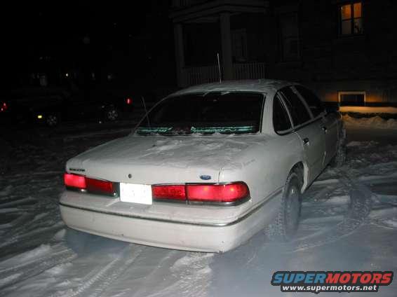 Rear of a white Ford Crown Victoria parked in snow at night