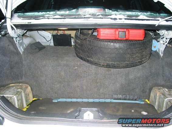 Trunk interior with spare tire, red toolbox, and a brush
