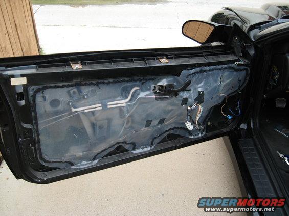 Car door with interior panel removed, showing wiring and vapor barrier