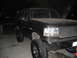 1993 Ford Bronco - This black Ford Bronco features a significant lift kit and aggressive off-road tires, viewed from a three-quarter front angle at night.