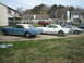 1965 Ford Mustang - Three Ford Mustangs, a blue convertible, a white convertible, and a silver coupe, are parked in a residential driveway.