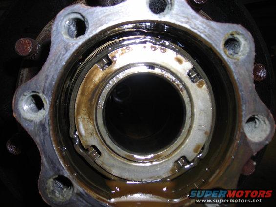 Close-up of a greasy wheel hub assembly with a bearing retainer ring