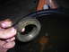 1995 Ford F-250 - A mechanic holds a damaged wheel bearing race, likely from a truck, over a pan of used oil.