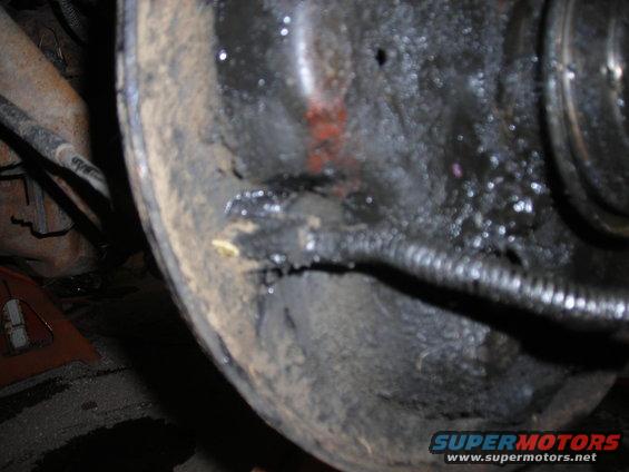 Close-up of a greasy brake drum assembly with a brake line visible