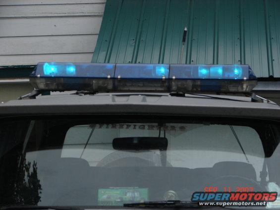 Emergency light bar with blue lights on top of a vehicle, "FIREFIGHTERS" text on rear window