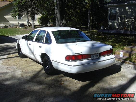 1997 Ford Crown Victoria, rear 3/4 view, white paint, black wheels, parked in driveway