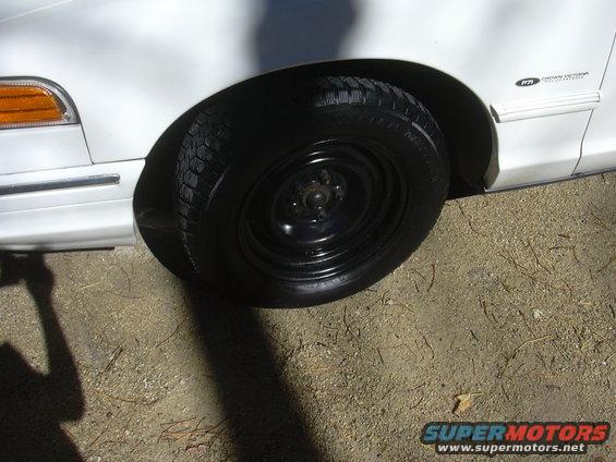 White 1997 Ford Crown Victoria front fender and wheel with a badge visible